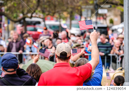 People waving USA flags in a large crowd at a rally. 124839054
