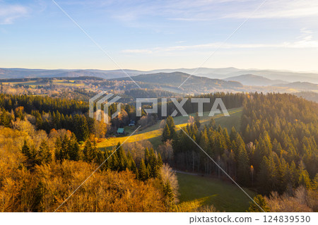 A sunny autumn morning unfolds over the Jizera Mountains, highlighting the Bramberk lookout tower and the surrounding vibrant forests. Nature's beauty captivates the landscape in golden hues. A sunny autumn morning unfolds over the Jizera Mountains, highlighting the Bramberk lookout tower and the surrounding vibrant forests. Nature's beauty captivates the landscape in golden hues. 124839530