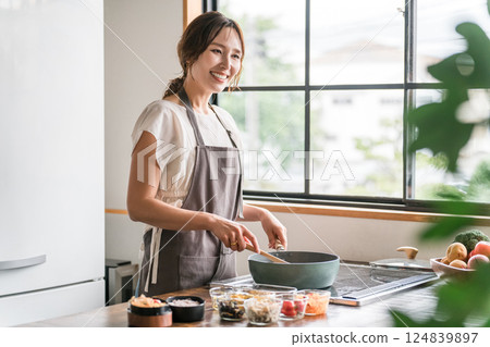 一位年輕的亞洲女性(母親、妻子、家庭主婦)在廚房裡做午餐盒 一位年輕的亞洲女性(母親、妻子、家庭主婦)在廚房裡做午餐盒 124839897