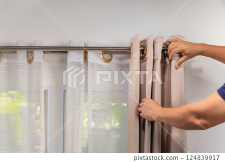 Worker repairman hanging and fixing the curtain on the window. Worker repairman hanging and fixing the curtain on the window. 124839917