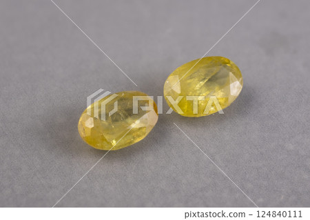 Pair of Natural Faceted Yellow Gemstones of Sphene on Gray Background Pair of Natural Faceted Yellow Gemstones of Sphene on Gray Background 124840111