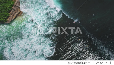 Breathtaking aerial view of surfers riding waves at the famous Dreamland Beach in Bali, Indonesia, showcasing the beauty of the ocean and the thrill of surfing 124840621