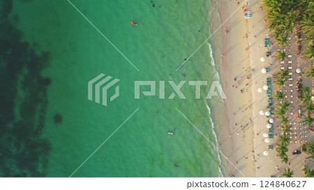 Aerial view of Cagban Beach in Boracay Island, Philippines, showing tourists enjoying the crystal clear turquoise water and white sand beach, lined with palm trees and beach umbrellas Aerial view of Cagban Beach in Boracay Island, Philippines, showing tourists enjoying the crystal clear turquoise water and white sand beach, lined with palm trees and beach umbrellas 124840627