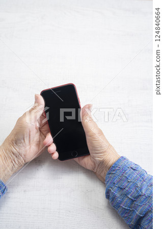 Hands of an elderly woman holding a smartphone 124840664