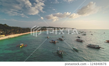 Aerial drone view of Cagban Beach in Boracay Island, Philippines, showcasing numerous traditional banca boats dotting the vibrant turquoise waters under a picturesque sunset sky Aerial drone view of Cagban Beach in Boracay Island, Philippines, showcasing numerous traditional banca boats dotting the vibrant turquoise waters under a picturesque sunset sky 124840678