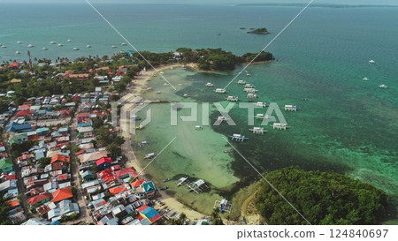 Stunning aerial view of a tropical paradise showcasing the vibrant cultural landscape of Malapascua Island, Philippines, with colorful houses, traditional boats, and crystal-clear turquoise waters 124840697