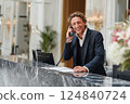 A smiling hotel receptionist making a phone call while working at the hotel counter in the lobby. Ai generated. 124840724