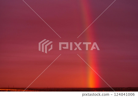 Vivid red sunset sky with striking rainbow column. 124841006