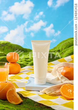 Cosmetic tubes stand upright on a rectangular tray. Rough cloth is spread over the tray, partially covering it. Oranges are cut in half, revealing fresh, juicy orange segments. Blue sky background. Cosmetic tubes stand upright on a rectangular tray. Rough cloth is spread over the tray, partially covering it. Oranges are cut in half, revealing fresh, juicy orange segments. Blue sky background. 124841418