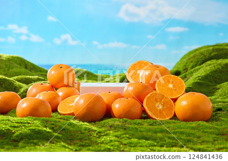 Ripe oranges with shiny orange peels, piled on top of each other. Oranges cut in half to reveal juicy orange segments placed around a rectangular platform. Green grass with artificial moss patches. 124841436