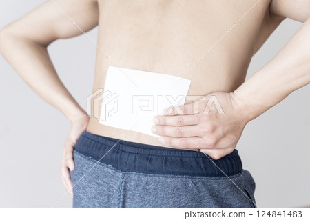 Man applying a compress to his lower back, lower back pain, compress, muscle pain Man applying a compress to his lower back, lower back pain, compress, muscle pain 124841483