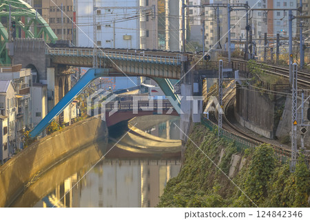 Red Train Passing by Canal in Urban City Neighborhood, Ochanomizu Dec 8 2024 124842346