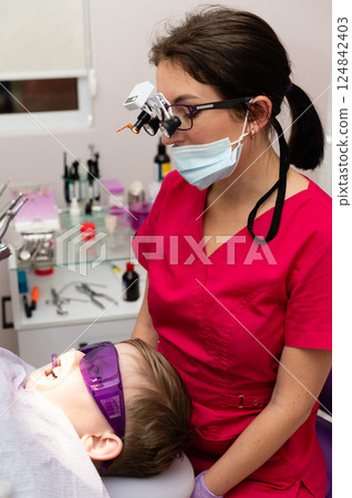 Bright smiles uplifted in a pediatric dental clinic where a skilled professional tends to a young patient using modern tools and techniques during a routine check-up 124842403