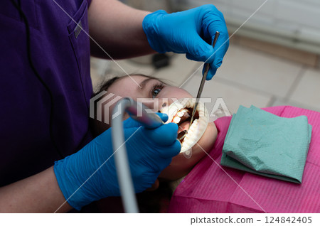 Child receiving dental care in a bright clinic with a focused dentist performing a thorough check-up on a summer afternoon 124842405