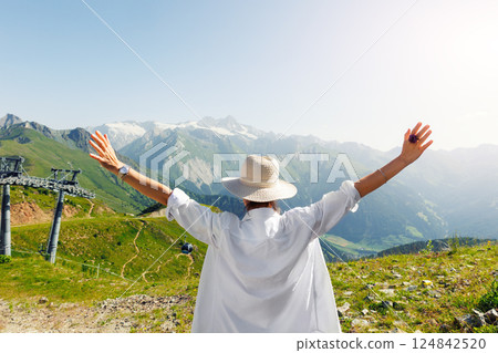 Scenic back view young adult woman white shirt raise hands enjoy exploring scenic alpine austrian mountain peak landscape view sunny warm sunset. Female happy person explore alps Grossglockner Summit. Scenic back view young adult woman white shirt raise hands enjoy exploring scenic alpine austrian mountain peak landscape view sunny warm sunset. Female happy person explore alps Grossglockner Summit. 124842520