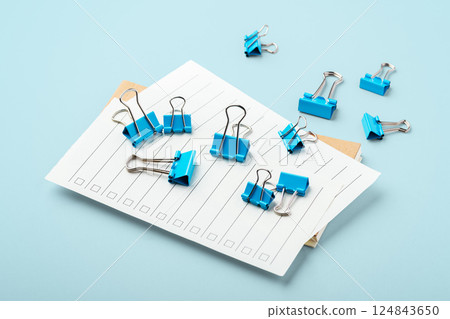 Binder clips on checklist paper on light blue background 124843650