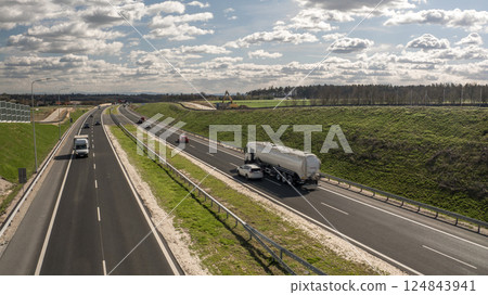 A Modern Highway with Moving Traffic Surrounded by Green Fields and Roadside Infrastructure A Modern Highway with Moving Traffic Surrounded by Green Fields and Roadside Infrastructure 124843941