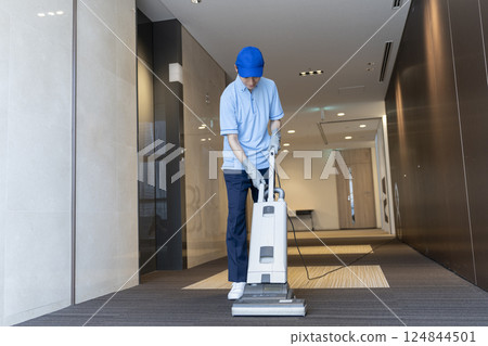 Male cleaning staff working with a commercial carpet vacuum cleaner 124844501