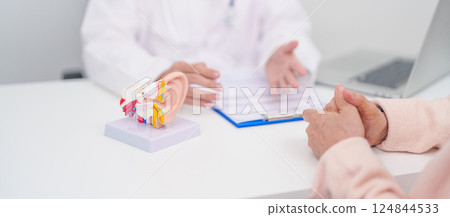 Elderly Patient consulting Doctor to Ear disease. Senior Health Medical Diagnosis. Anatomy Ear model for Atresia, Otitis Media, Pertorated Eardrum, Meniere syndrome, otolaryngologist, Hearing Loss 124844533