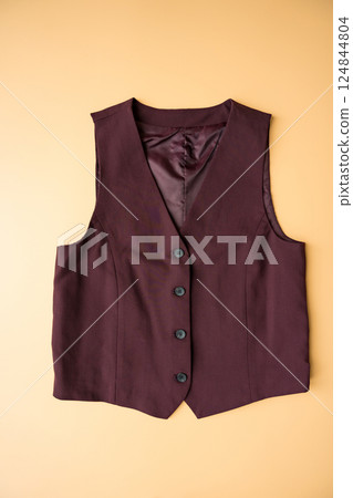 Burgundy buttoned female vest on apricot background, second-hand fashion and sustainable style Burgundy buttoned female vest on apricot background, second-hand fashion and sustainable style 124844804