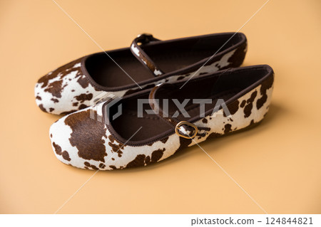 Cow print nappy ballet flats with buckle detail on apricot background. 124844821