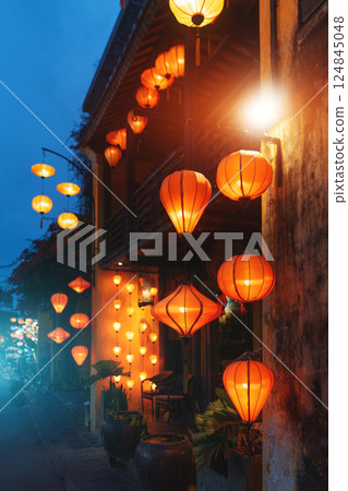 Hanging lanterns glowing on Vietnamese old town street at dusk, Traditional lanterns lighting up evening street in Hoi An 124845048