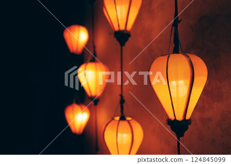 Glowing orange lanterns creating warm decorative background, Vertical hanging lanterns forming ambient light pattern Glowing orange lanterns creating warm decorative background, Vertical hanging lanterns forming ambient light pattern 124845099