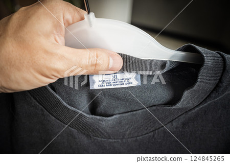 Close-up of a clothing label showing the text "Assembled in Mexico of USA materials" held by a hand, symbolizing global trade and recent tariff conflicts Close-up of a clothing label showing the text "Assembled in Mexico of USA materials" held by a hand, symbolizing global trade and recent tariff conflicts 124845265
