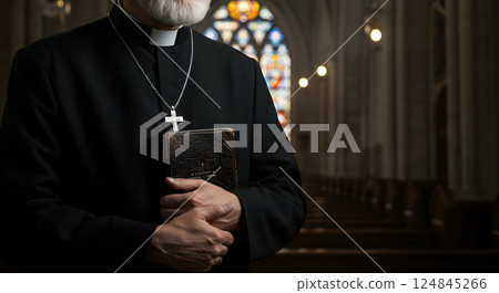 Close up portrait of Catholic clergyman. Christian priest in black clerical clothing with silver cross necklace and Bible book on hands in temple or church. Religious and traditional faith concept. 124845266