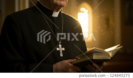 Close up portrait of Catholic clergyman. Christian priest in black clerical clothing with silver cross necklace and Bible book on hands in temple or church. Religious and traditional faith concept. 124845273