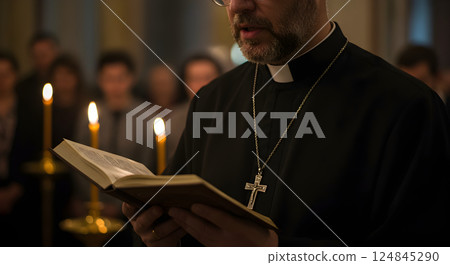 Christian priest in clerical clothing with cross necklace and Bible in temple or church performing sacred easter ritual with candles. portrait of Catholic clergyman. Religious and traditional concept. 124845290