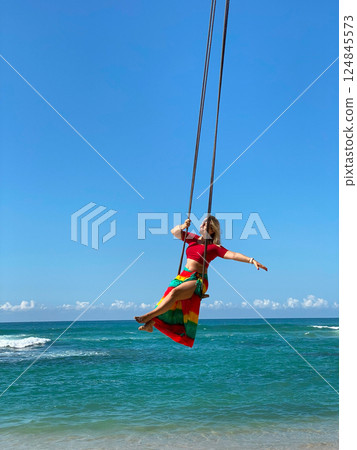female traveller in a dress and wide-brimmed hat on a swing 124845573