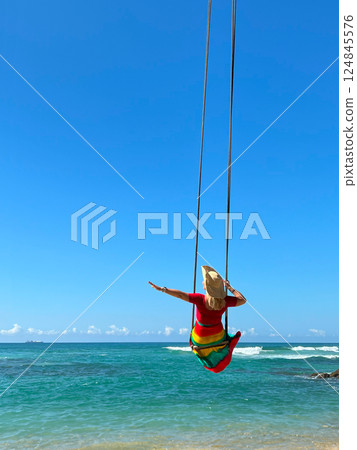 female traveller in a dress and wide-brimmed hat on a swing female traveller in a dress and wide-brimmed hat on a swing 124845576