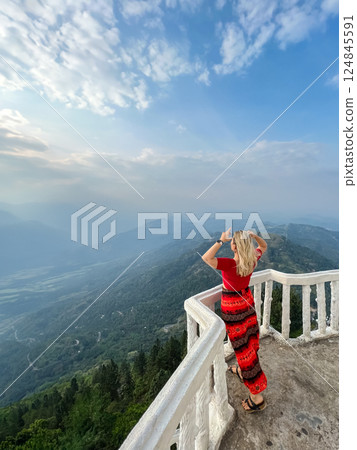 A blonde woman enjoys the view from a tower at the Ambuluwawa Temple A blonde woman enjoys the view from a tower at the Ambuluwawa Temple 124845591
