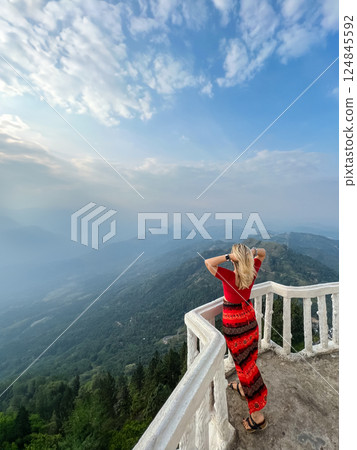 A blonde woman enjoys the view from a tower at the Ambuluwawa Temple 124845592