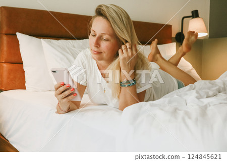 woman using smartphone in bedroom 124845621