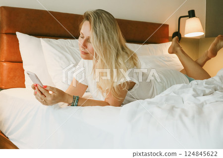woman using smartphone in bedroom 124845622
