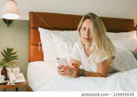 woman using smartphone in bedroom woman using smartphone in bedroom 124845639