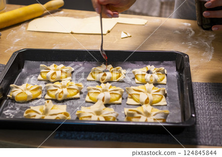Shot of the a pineapple wedges wrapped in puff pastry on the baking tray 124845844
