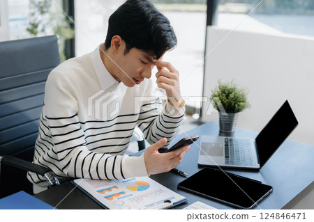 Serious young man sit at workplace desk in office use calculator calculates monthly expenses, taxes, personal budget management concept 124846471