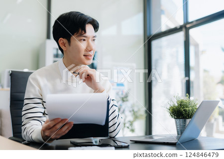 Portrait of a young man thinking sitting at his desk in the office. 124846479