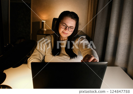 Cheerful millennial woman enjoy videocall with friends using laptop. Gesturing and smiling. Talking with friends who living far. Cherishing long distance friendship. 124847788