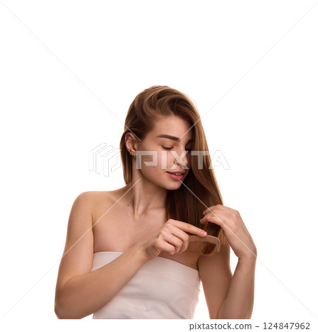 Photo of young pretty woman, combing her, long, well groomed shiny hair against white background. Hairstyling. Photo of young pretty woman, combing her, long, well groomed shiny hair against white background. Hairstyling. 124847962