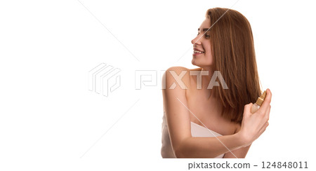 Young woman with long shiny brunette hair, spraying cosmetic product on hair against white background. Hairstyling. Young woman with long shiny brunette hair, spraying cosmetic product on hair against white background. Hairstyling. 124848011