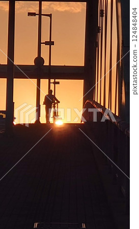 A boy pushing a bicycle in the sunlight of the setting sun A boy pushing a bicycle in the sunlight of the setting sun 124848404