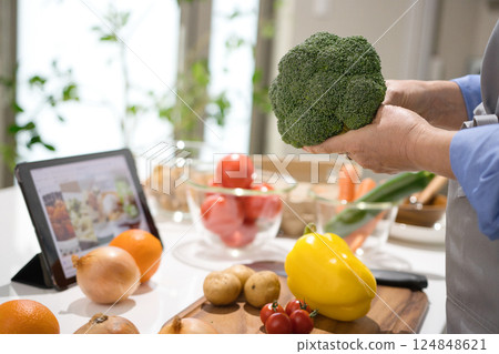 Middle woman cooking while looking at a tablet 124848621