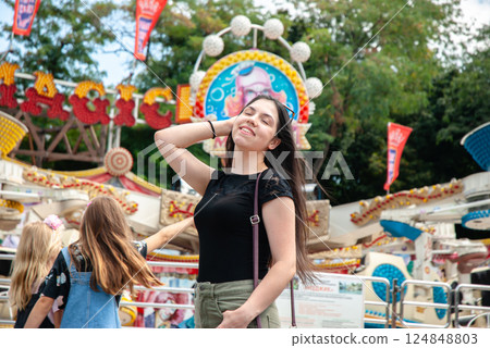 Happy young woman enjoying a day at the amusement park with friends. Happy summer days, travel and vacation concept 124848803