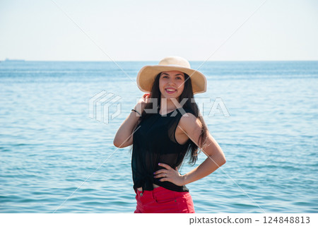 Smiling woman in sun hat enjoying a day at the beach. Happy summer days, travel and vacation concept 124848813