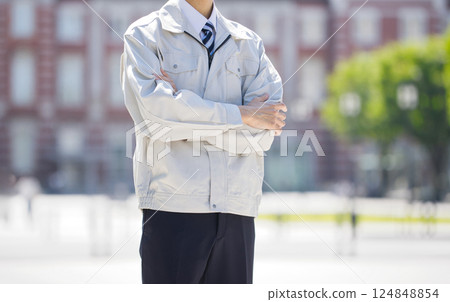 一名身穿工作服的男子雙手交叉站在建築工地上 124848854