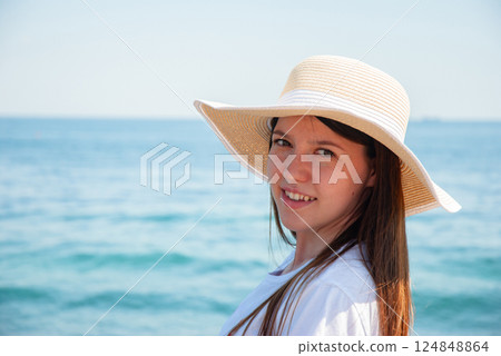 Woman enjoying a day at the beach wearing a sun hat by the ocean. Happy summer days, travel and vacation concept Woman enjoying a day at the beach wearing a sun hat by the ocean. Happy summer days, travel and vacation concept 124848864